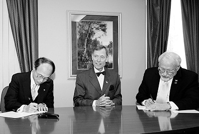 Photograph: Yukata Takenaka (left) and Thomas Romig (right) sign agreement while Washburn President Jerry Farley looks on.